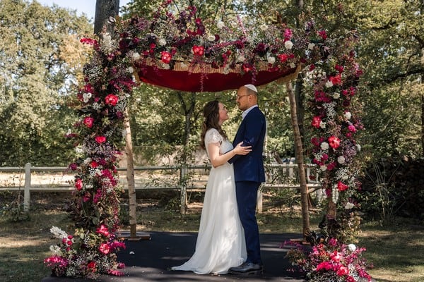 Red and white floral arch for outdoor ceremony
